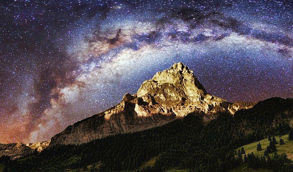 Ciel étoilé et voie lactée au dessus d'un sommet de montagne dans les Alpes.